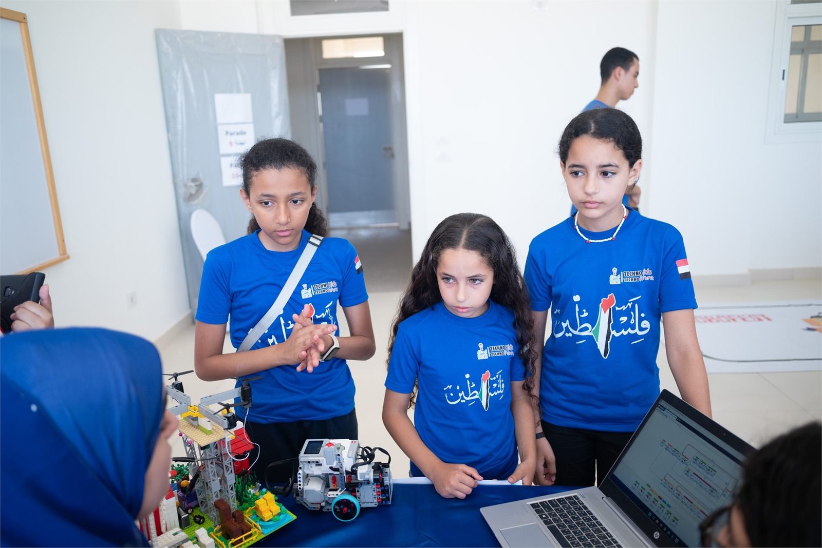 Ibdaa Academy students collaborating around a laptop and their robots